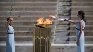 Greek actress Xanthi Georgiou (R), dressed as an ancient Greek high priestess lights the olympic torch during the Flame Handover Ceremony for the Tokyo 2020 Summer Olympics on March 19, 2020 in Athens, Greece. The ceremony was held behind closed doors as a preventive measure against the Coronavirus outbreak. (Photo by Aris Messinis - Pool/Getty Images Europe)