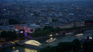 Athletes travel by boat down the Seine River