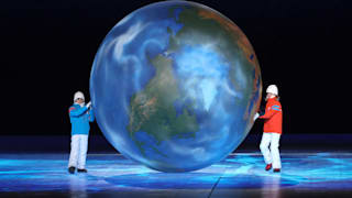 Children representing Milan and Cortina hug a globe as part of the handover ceremony