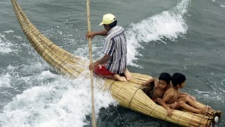 A fisherman kneels on top of a "reed horse", an ancient cigar shaped boat still used in northern Peru, and steers it through the waves with two children riding in its hollow interior, January 28, 2001. The hollow kayaks, with their characteristic pointed prows rising out of the water, are believed to have been the precursors of surfboards used by the ancient inhabitants of northern Peru to ply the choppy Pacific. They are similar to the boats depicted on ceramics from Peru's Moche civilization 1,500 years ago. The inhabitants of Huanchaco are among the few remaining people on the coast who still know how to build and pilot these precarious-looking craft.