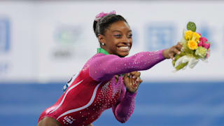 Simone Biles swats away a bee during awards at the 2014 Worlds