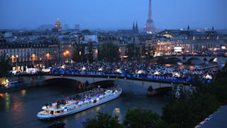 Spectators look on as athletes from Team France pass by on a boat on the River Seine