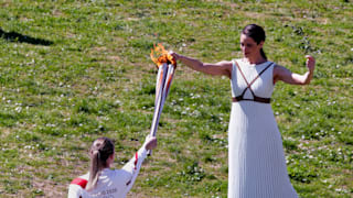 Xanthi Georgiou, playing the role of High Priestess passes the flame to the first torchbearer, Greek shooting athlete Anna Korakaki, during the opening of the Olympic flame torch relay. Photo by Getty Images.