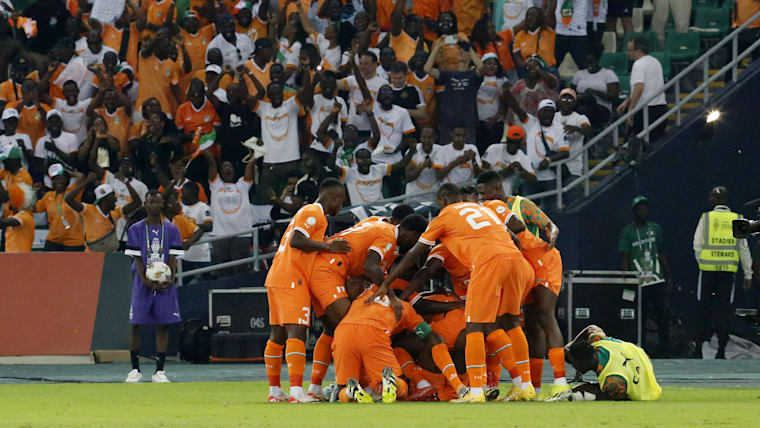 Côte d'Ivoire players mob Seko Fofana after his early goal with the crowd cheering their approval in the background