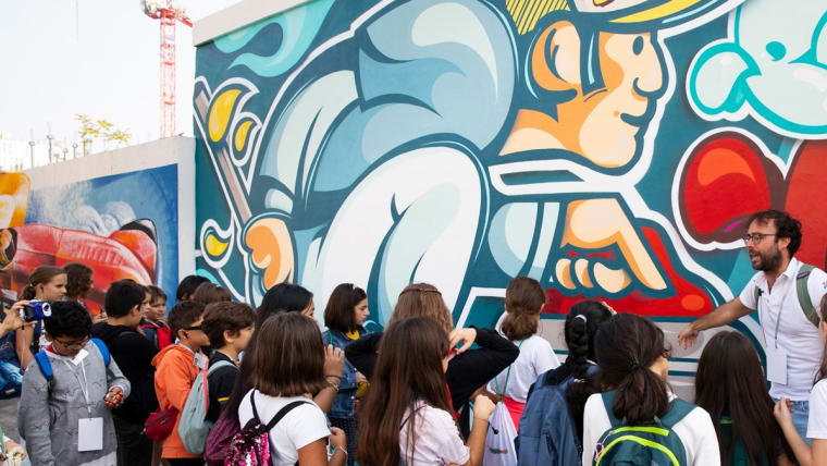 Foto di un gruppo di bambini mentre guardano il murales