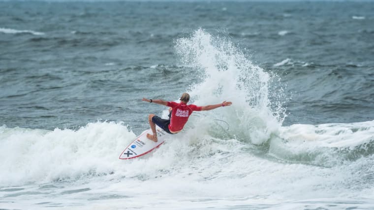A male surfer carves a low wave.