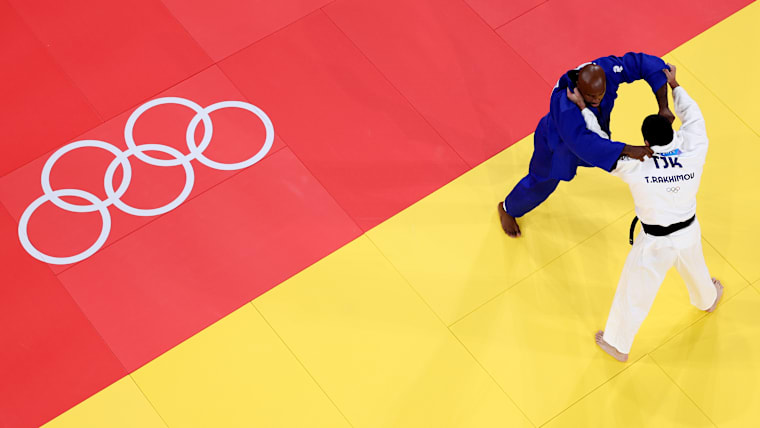 Image was captured using a robotic camera positioned above the field of play.) Tedddy Riner (blue) of Team France and Temur Rakhimov (white) of Team Tajikistan compete in the Judo Men +100kg Semifinal on day seven of the Olympic Games Paris 2024 at Champs-de-Mars Arena on August 02, 2024 in Paris, France. (Photo by Dan Mullan/Getty Images)