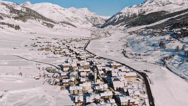 Beautiful winter scenery of the Livigno valley with mountains and a frozen river.