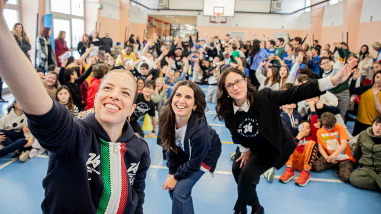 Three women take a selfie with a group of kids
