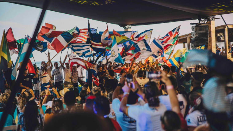 A group of athletes, some on stage, some in the audience, waving flags.