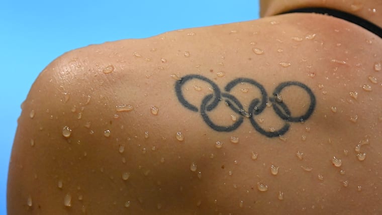 A close-up of the Olympics ring tattoo on a male swimmer's left shoulder blade.