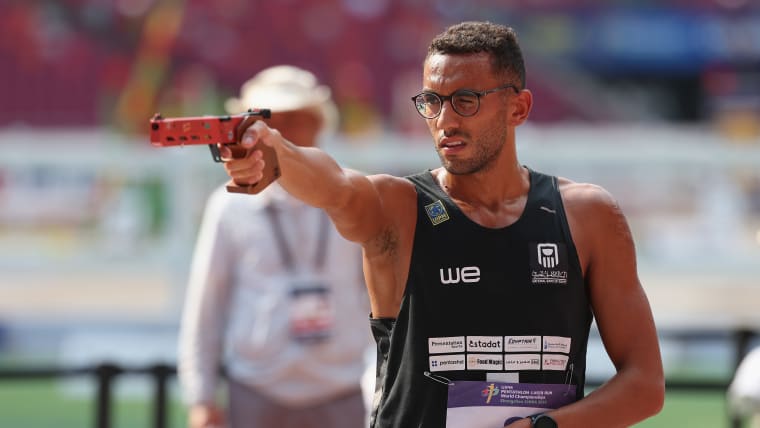 A male athlete aims his pistol at a target during the shooting portion of the laser run in modern pentathlon.