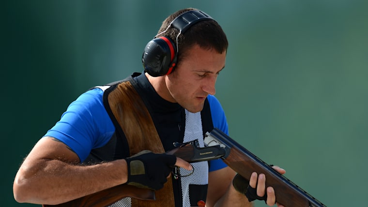 A male shooter looks down the barrel of his shotgun.