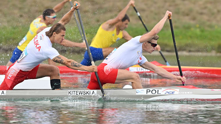Four athletes in two boats paddle in a race.