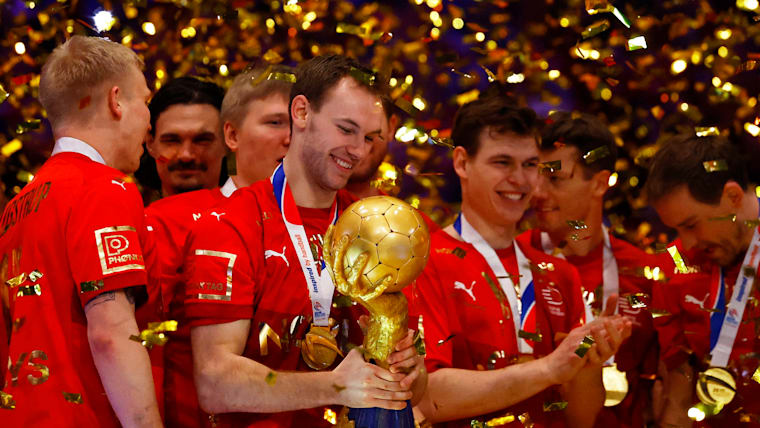 Gidsel smiles as he holds the trophy surrounded by Denmark teammates