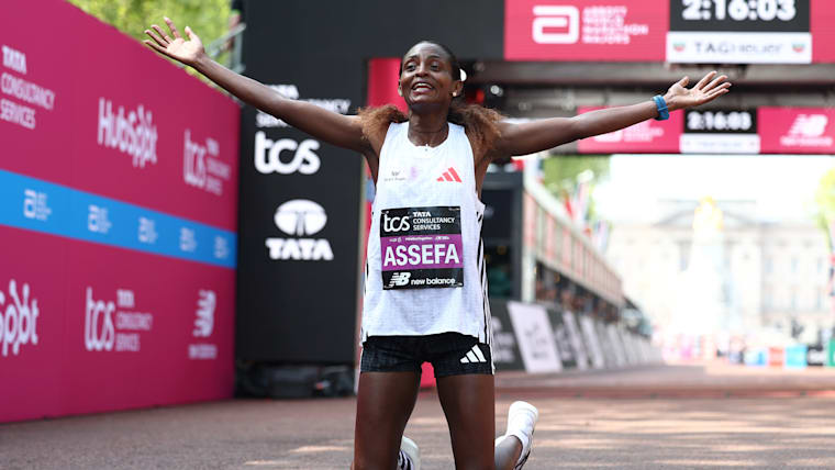 Assefa sinks to her knees with her arms outstretched as she celebrates victory.