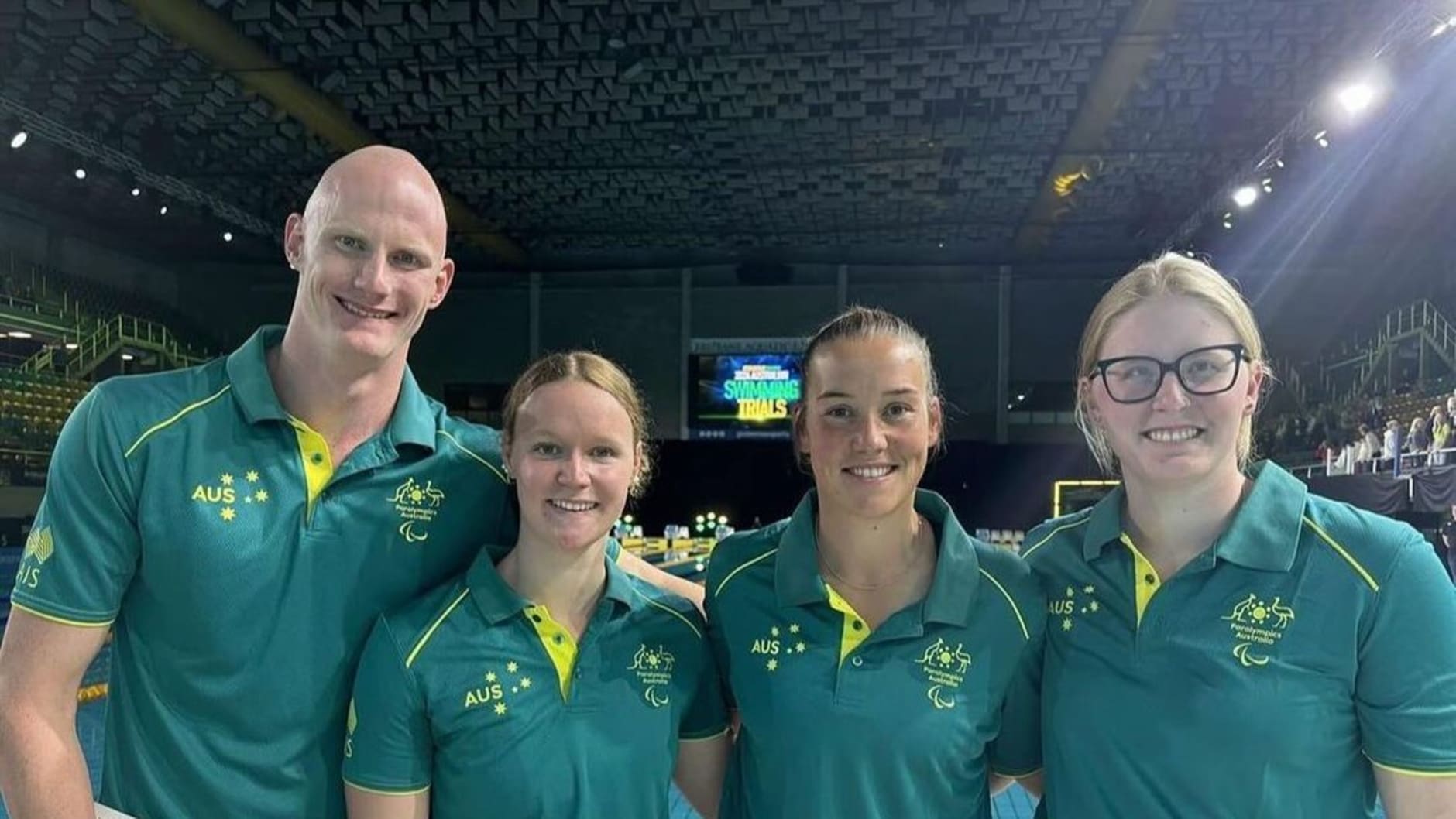 Paralympic swimmers from Yeronga Park pose together with their coach Kate Sparkes. Rowan Crothers, who is bald, is on the far left. Next to him is a dirty blonde haired Poopy Wilson. Then Kate Spades, who has brown hair. On the far right is Katja Dedekind wearing black framed glasses.