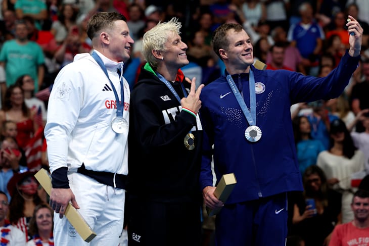 Adam Peaty, Niccolò Martinenghi, and Nic Fink pose on the podium after the men's 100m breaststroke victory ceremony