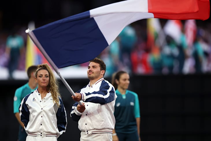  Flagbearers Antoine Dupont and Pauline Ferrand Prevot of Team France wave their national flag 