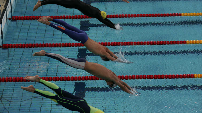 Male swimmers dive off the starting blocks to compete in an Olympic race in Athens 2004.
