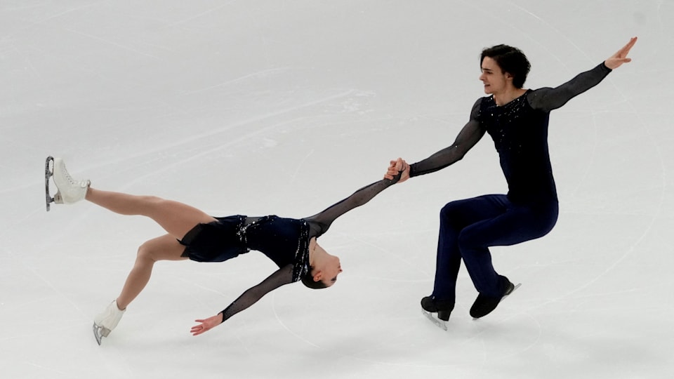 Pairs skaters perform a death spiral on the ice.