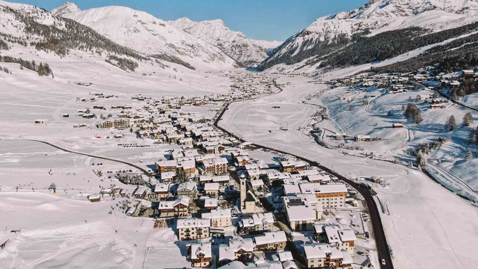 Beautiful winter scenery of the Livigno valley with mountains and a frozen river.
