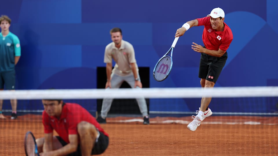 Kei Nishikori of Team Japan (R) serves as partner Taro Daniel of Team Japan looks on against Dan Evans and Andy Murray of Team Great Britain during the Menâ€™s Doubles first round match on day two of the Olympic Games Paris 2024 at Roland Garros on July 28, 2024 in Paris, France. 