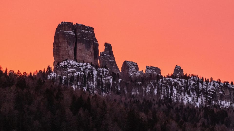A red sunset over the mountains and snow-covered trees in Cortina d'Ampezzo.