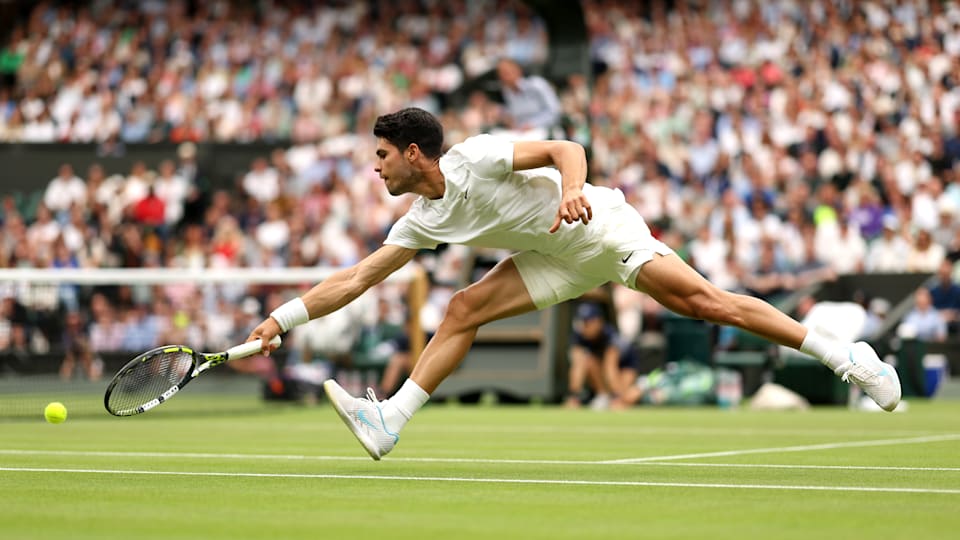 Carlos Alcaraz of Spain stretches to play a backhand against Frances Tiafoe of United States in his Gentlemen's Singles third round match during day five of The Championships Wimbledon 2024 at All England Lawn Tennis and Croquet Club on July 05, 2024 in London, England
