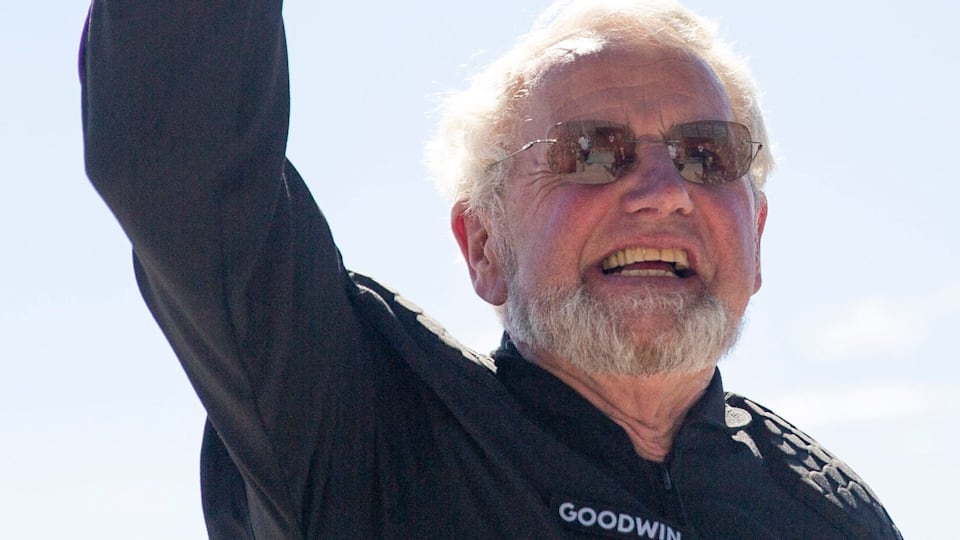 An elderly man waves before boarding a space craft.