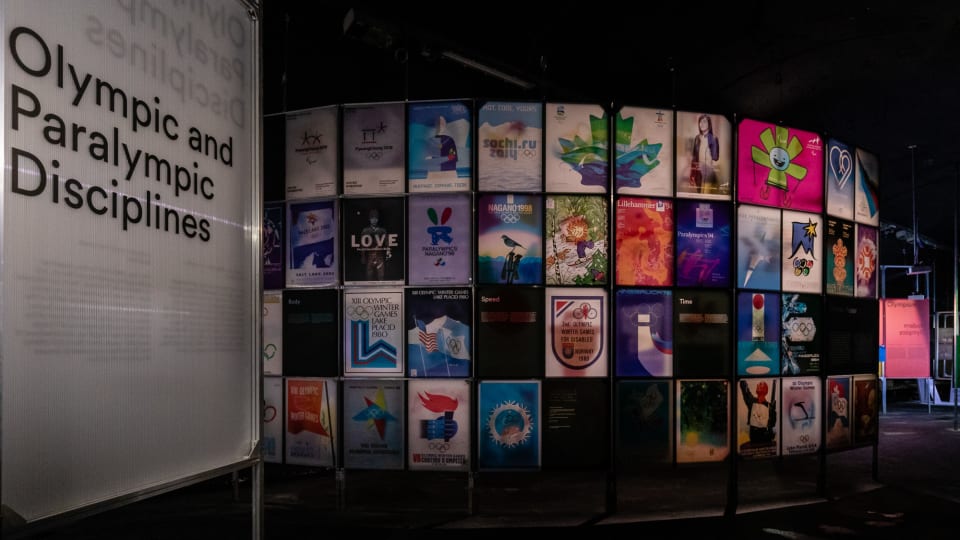 Foto di un pannello con diversi poster iconici delle edizioni delle Olimpiadi passate.