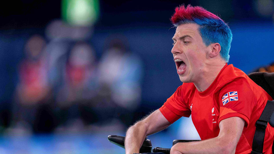 A male boccia player with a red-and-blue mohawk shouts during a boccia match.