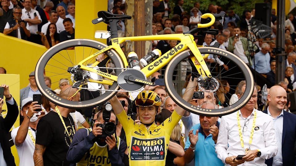 Vingegaard, wearing the yellow jersey, lifts his bike in the air as he celebrates victory in the 2023 Tour de France