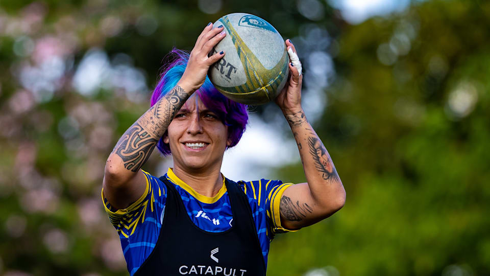 Campos holds a rugby ball just above her head