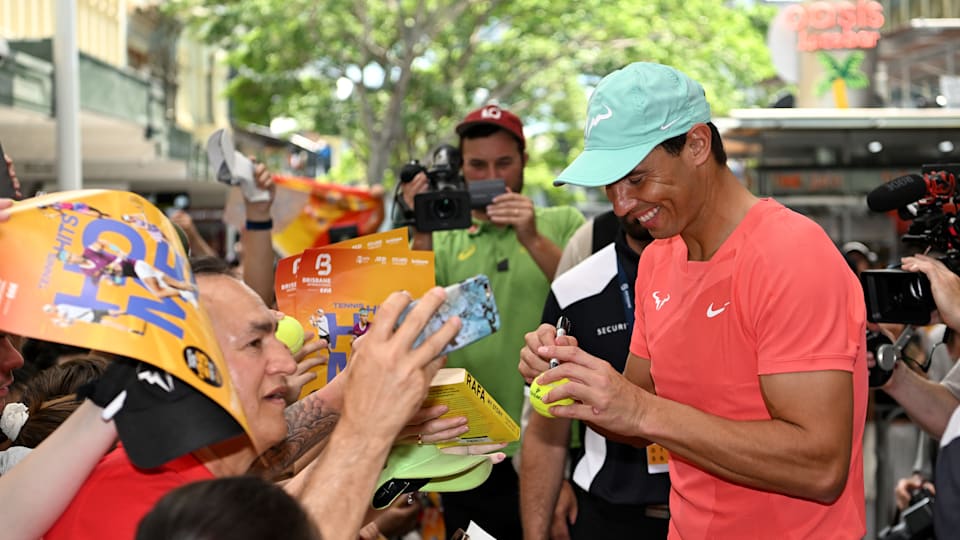 Rafael Nadal signs a tennis ball as fans queue for selfies and autographs in Brisbane city centre
