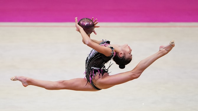 Beautiful Female Rhythmic Gymnast with Clubs Behind Her Back