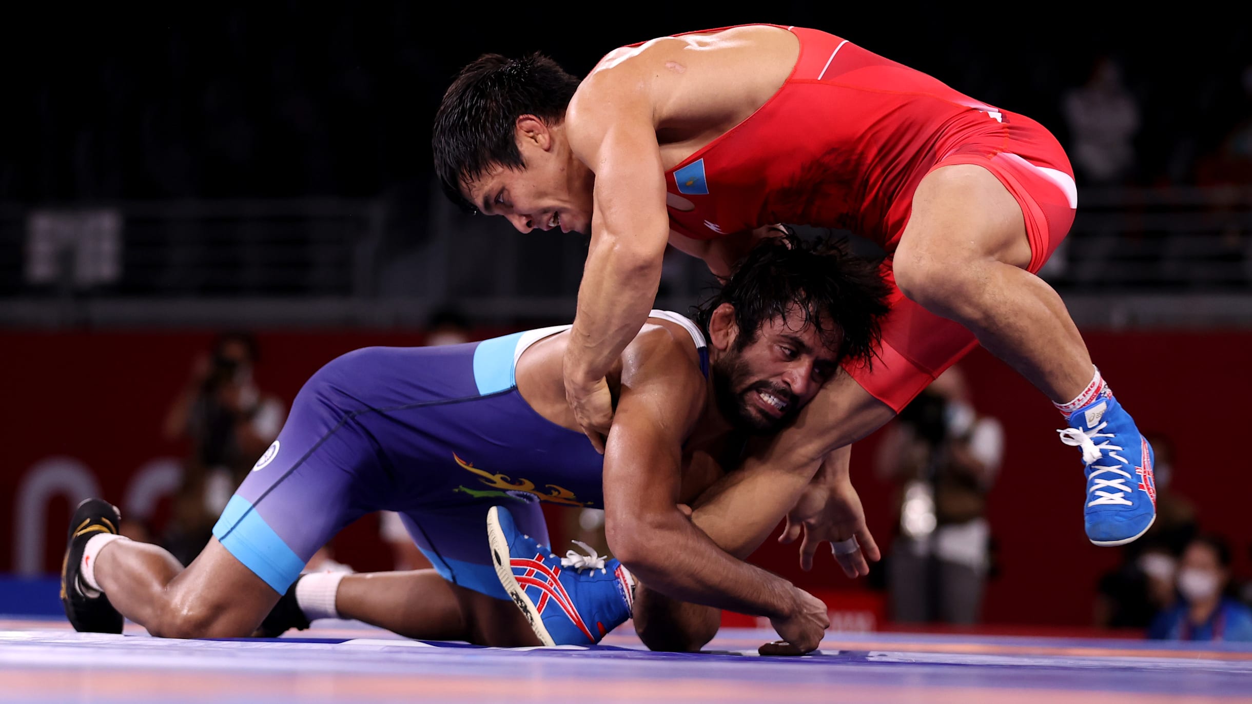 Men in wrestling tights and wrestlers holds the foot of a wrestler