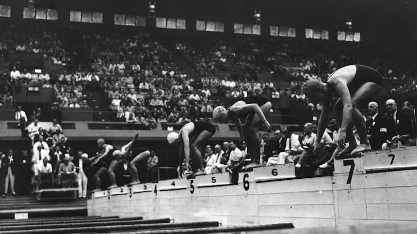 A black and white photo of female athletes lining up on the starting blocks before an Olympic swimming race in 1948