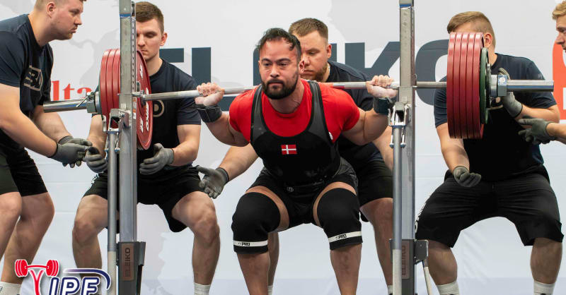 пауэрлифтер на помосте со штангой во время соревнований