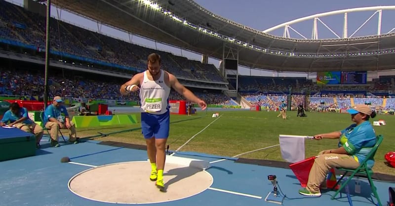 мощный спортсмен толкает ядро на стадионе